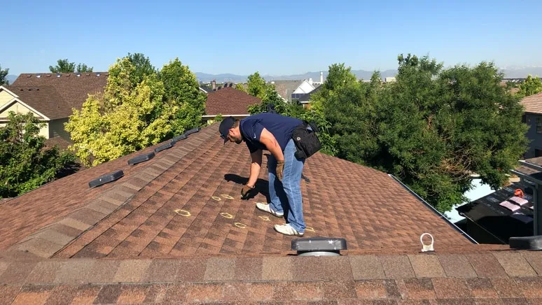 roofer on a roof inspecting it for insurance