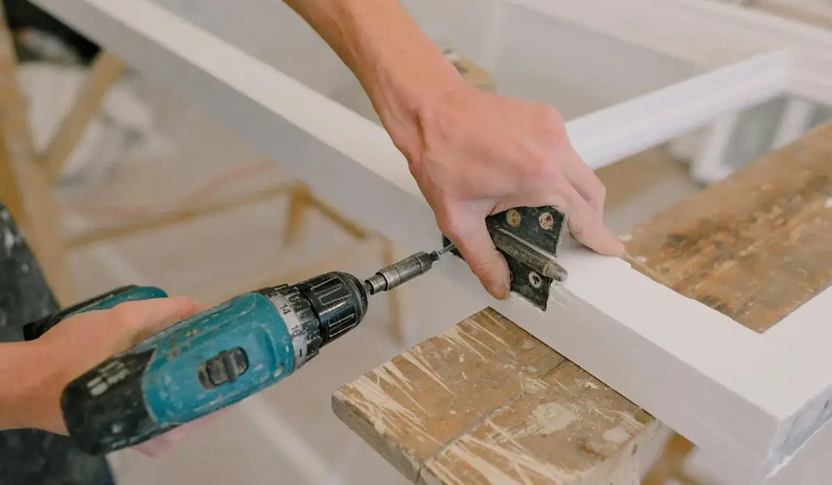 a man using cordless drill to screw door hinge