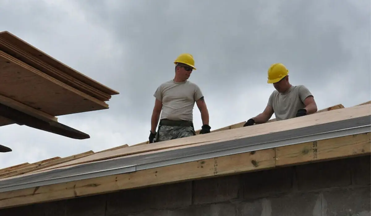 two roofers on top of roof wearing construction gear