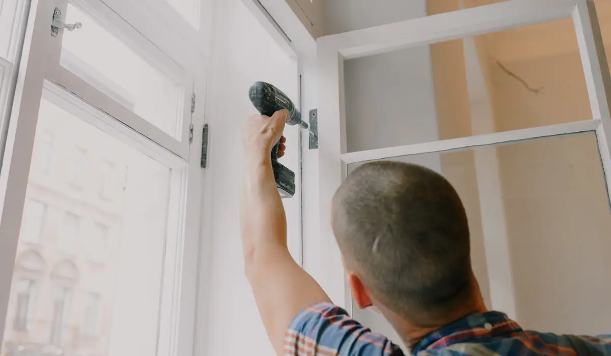 a man installing a window using a drill