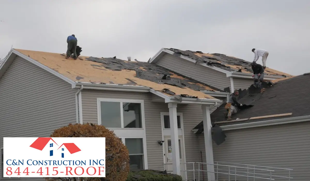 four male roofers repairing the house roof