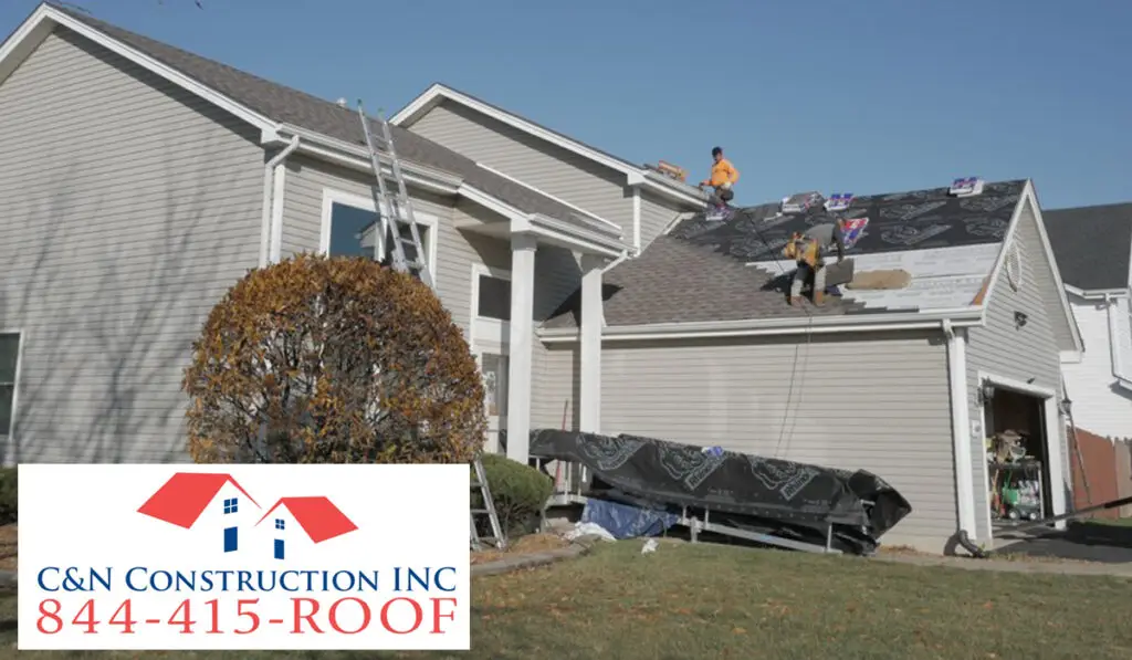 two male roofers repairing the house roof